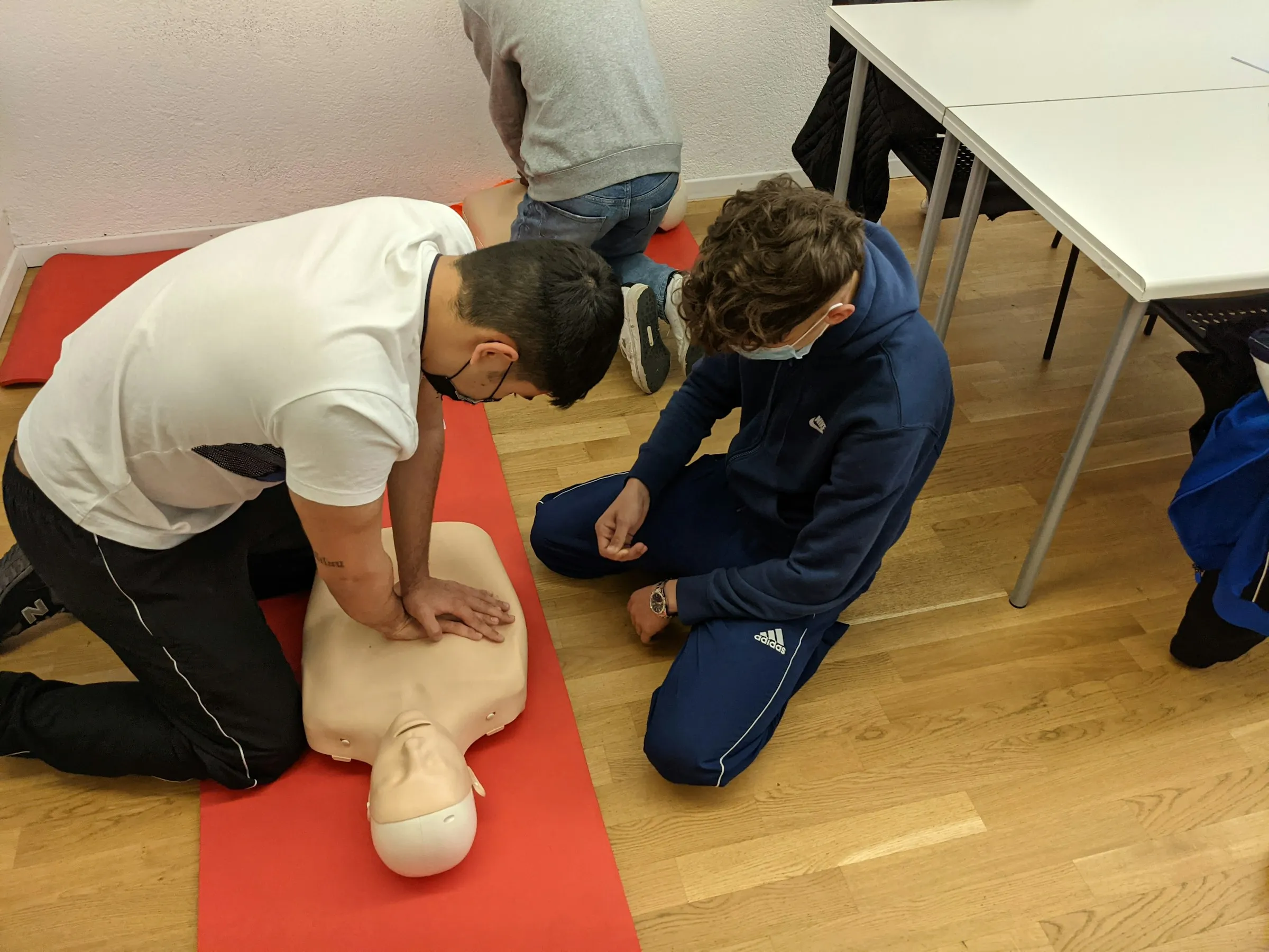 Kursteilnehmer üben die Herzdruckmassage an einer Reanimationspuppe im Erste-Hilfe-Kurs